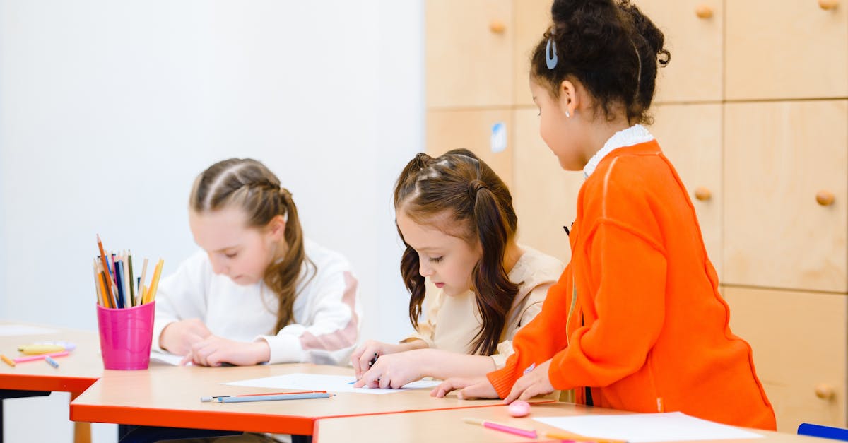 Three girls participate in a creative drawing session at a classroom table.